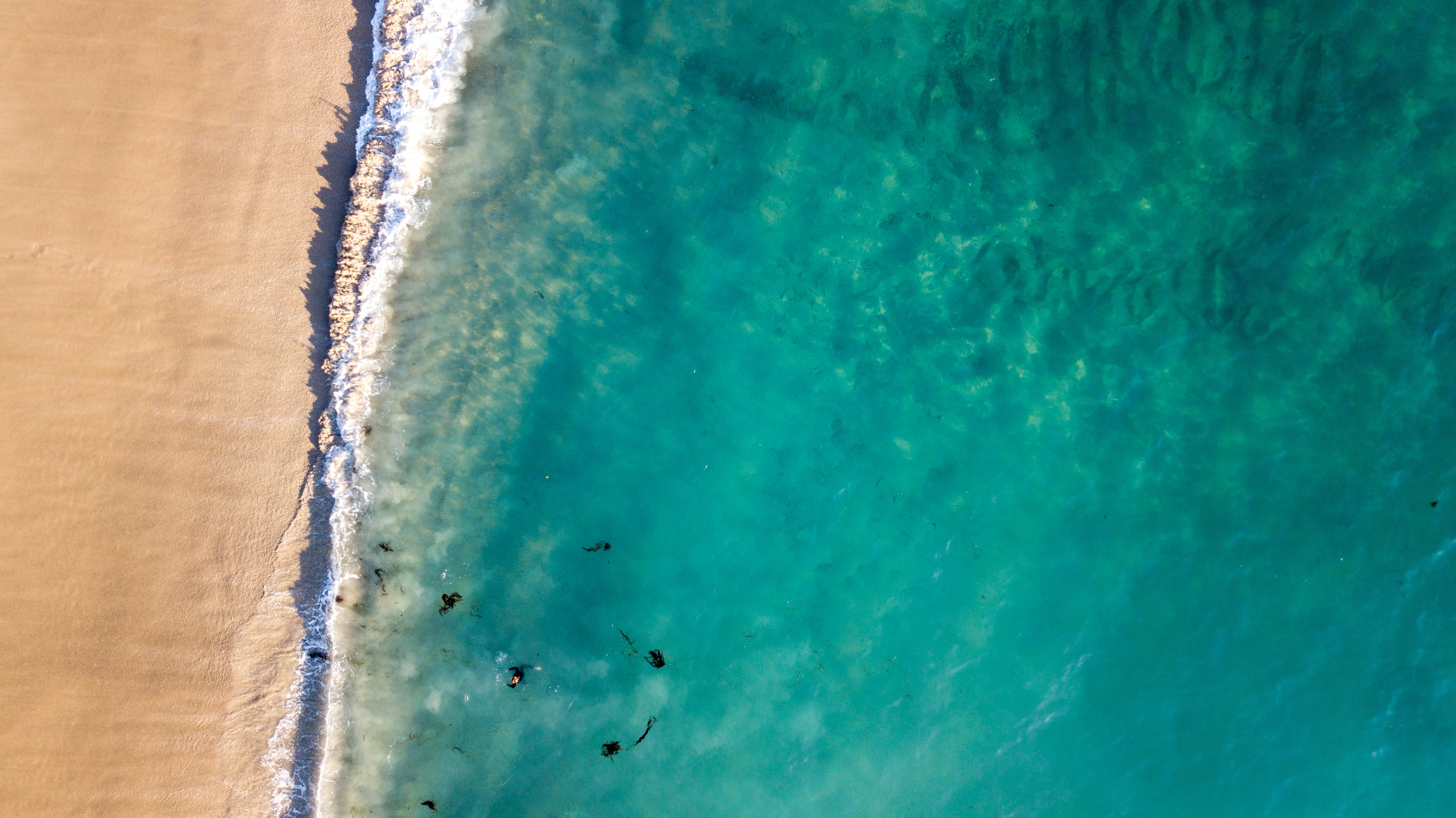 Sand and deep blue ocean waves, with swimmers
