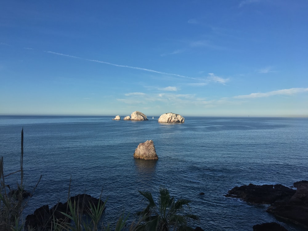 brown rock formation on sea under blue sky during daytime