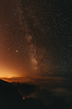 silhouette of mountain under starry night