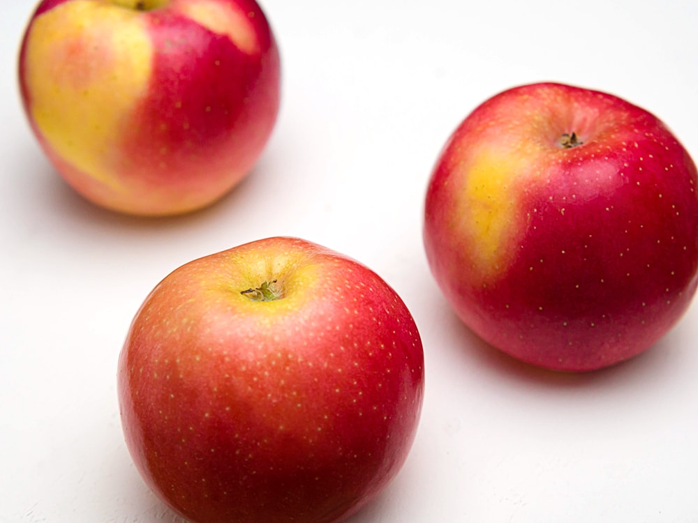 fruit de pomme rouge sur surface blanche