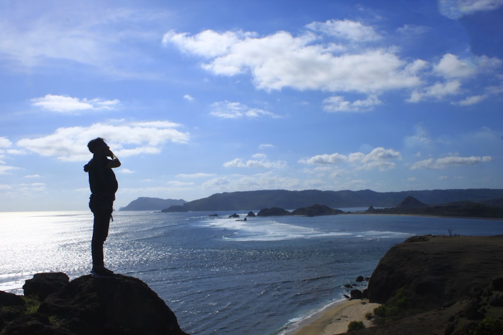 man in black jacket standing on seashore during daytime