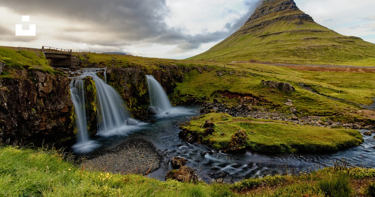 Foto zum Thema Grünes grasfeld in der nähe von wasserfällen unter