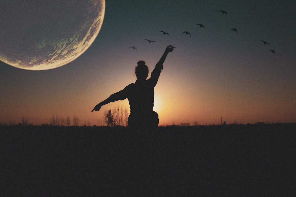 silhouette of person raising hands during night time