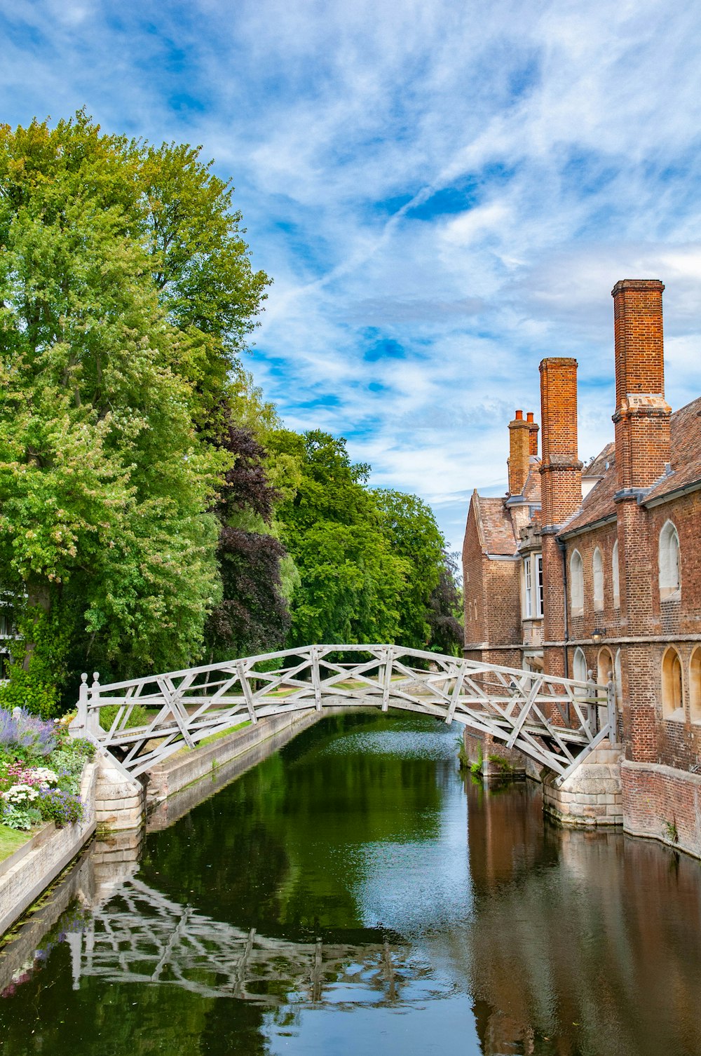 brown concrete bridge over river between green trees under blue sky during daytime