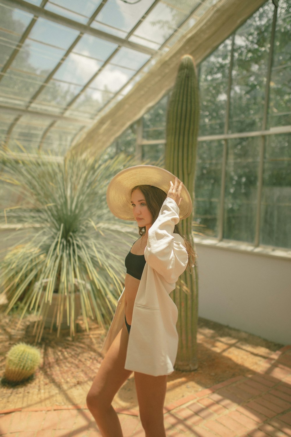 woman in white long sleeve dress wearing brown sun hat standing near green palm plants during