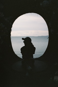 silhouette of man sitting on rock during sunset