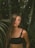 woman in black tank top standing beside green plant