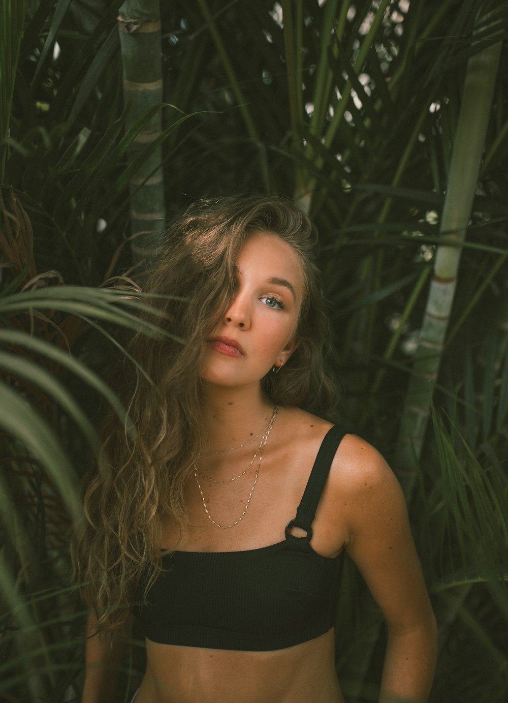 woman in black tank top standing beside green plant