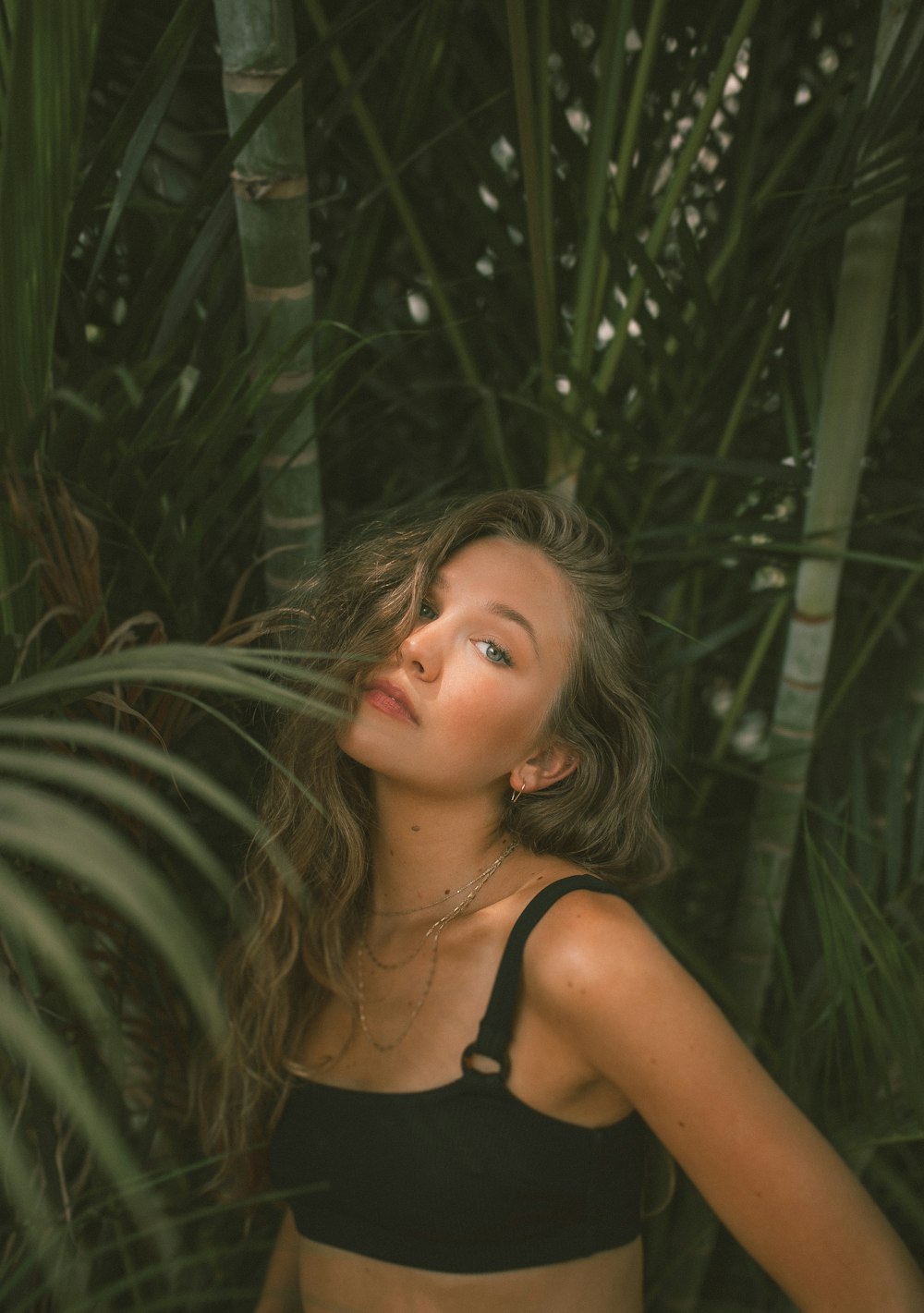 woman in black tank top standing beside green plant