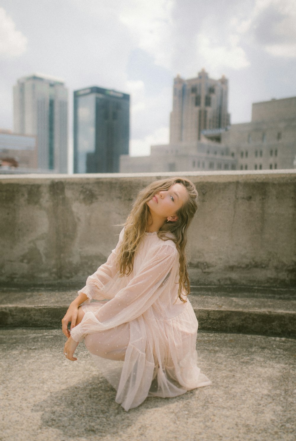 woman in pink long sleeve dress sitting on concrete bench during daytime