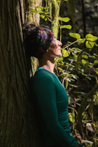 woman in green long sleeve shirt standing beside tree