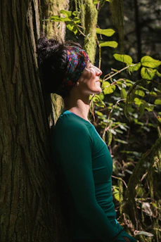 woman in green long sleeve shirt standing beside tree