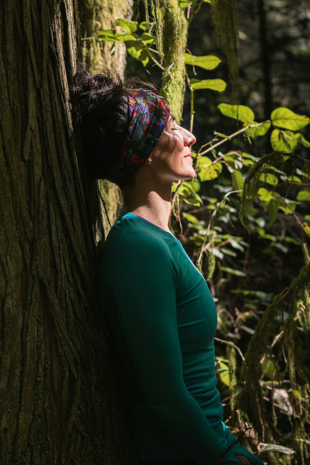 woman in green long sleeve shirt standing beside tree