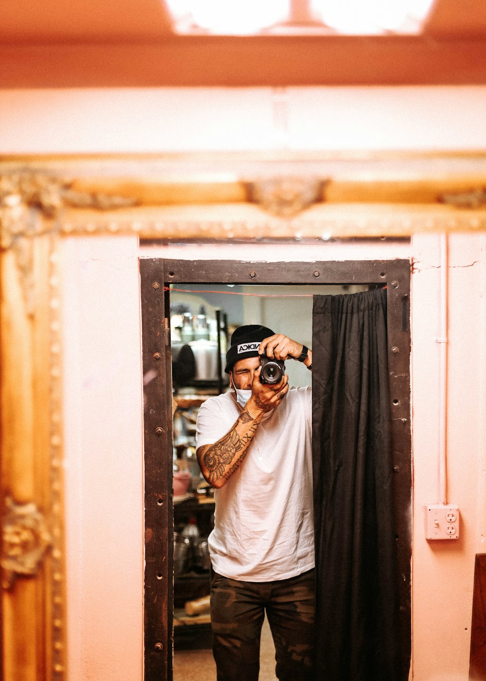 man in white shirt wearing black sunglasses standing near brown wooden door