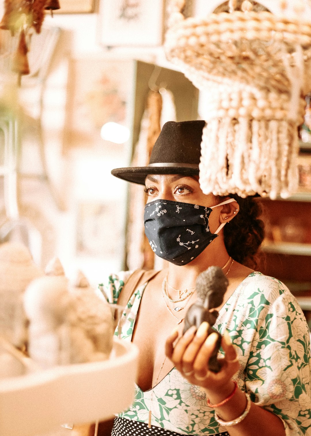 woman in white and green floral dress wearing black hat