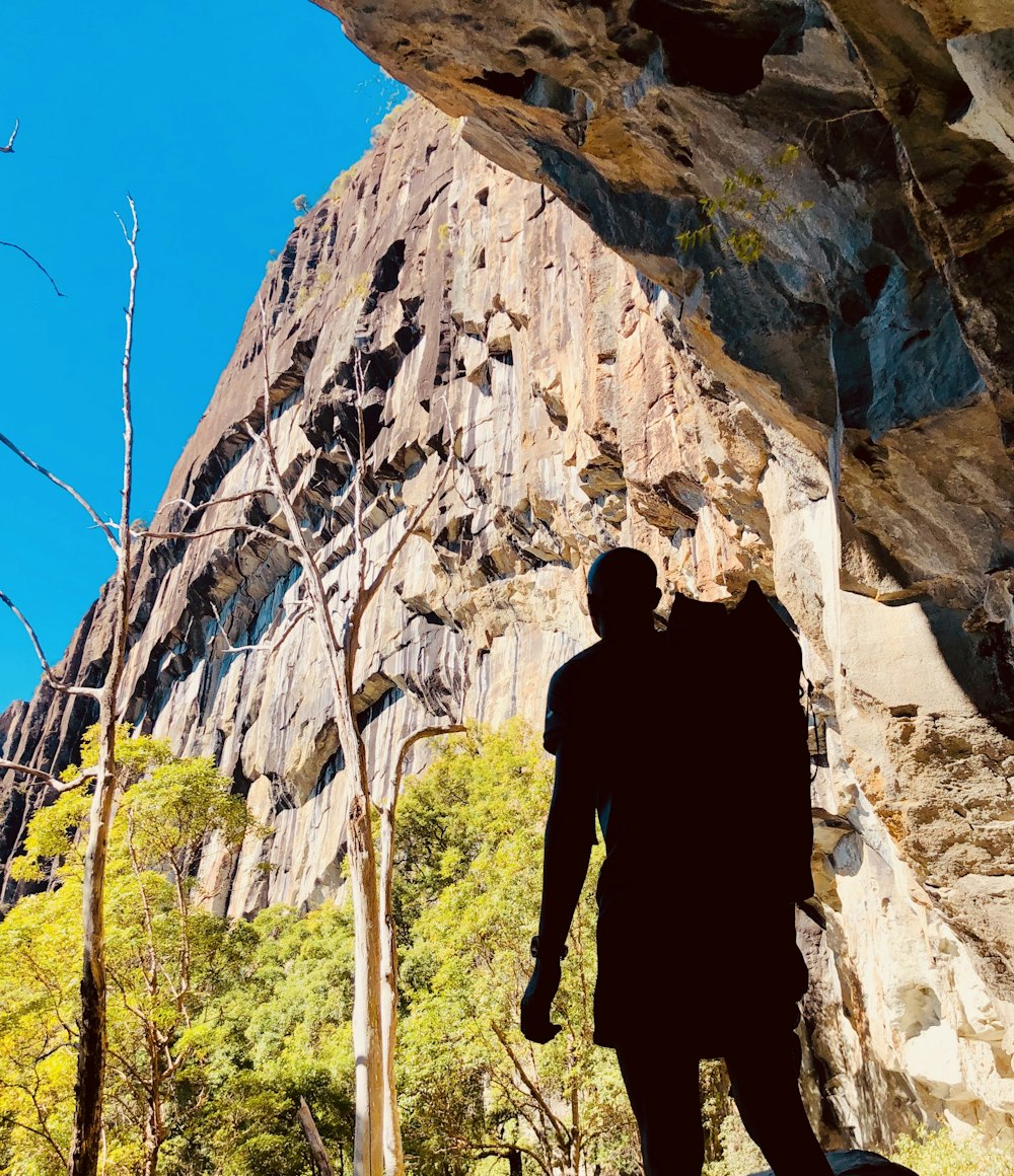 man in black jacket standing on brown rock formation during daytime