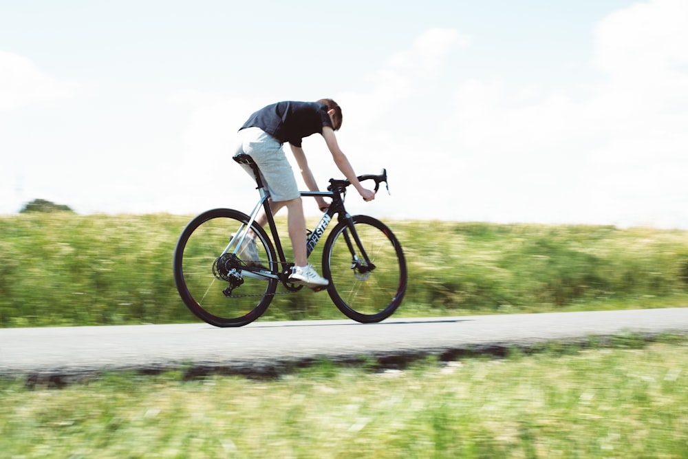 man in black shirt riding on black mountain bike on gray asphalt road during daytime