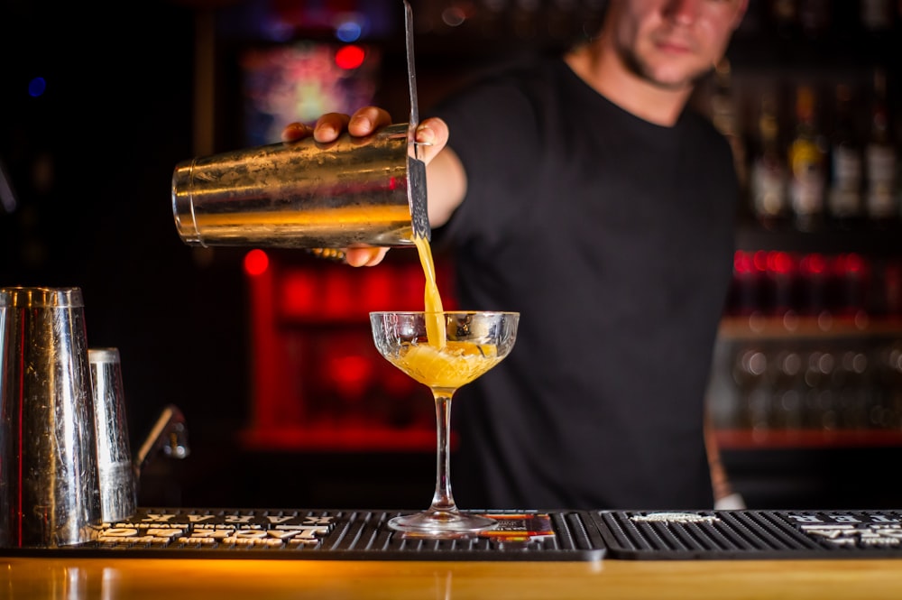 man in black crew neck shirt holding clear wine glass