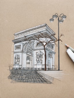 A detailed sketch of a historical arch structure, resembling the Arc de Triomphe, is depicted against a textured brown background. The drawing includes intricate architectural details and sculptures. A barren tree is drawn in front of the arch, and there is a tall streetlamp beside it. A white marker pen is positioned next to the sketch.