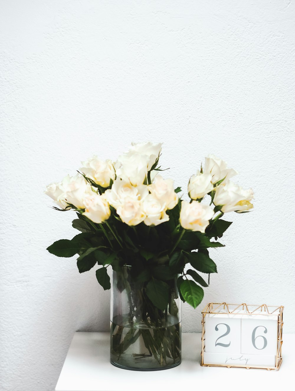 white roses in clear glass vase