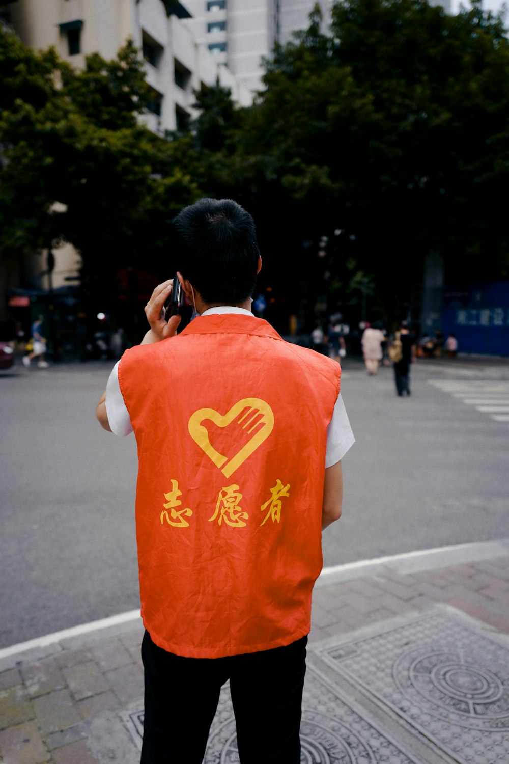 man in orange t-shirt standing on road during daytime