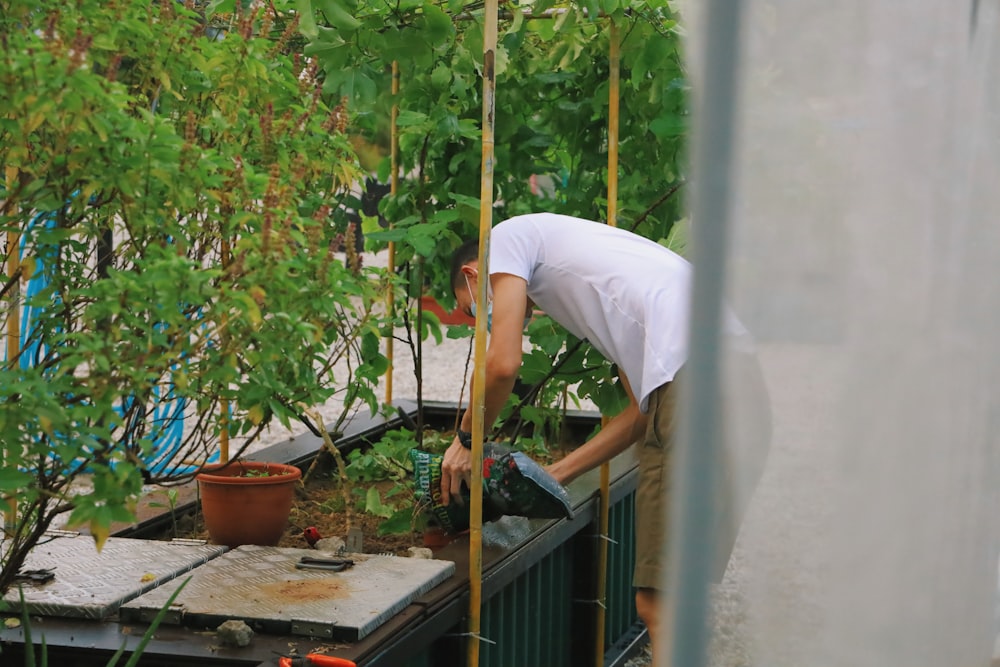 Mann in weißem T-Shirt und weißer Hose mit braunem Holzstab