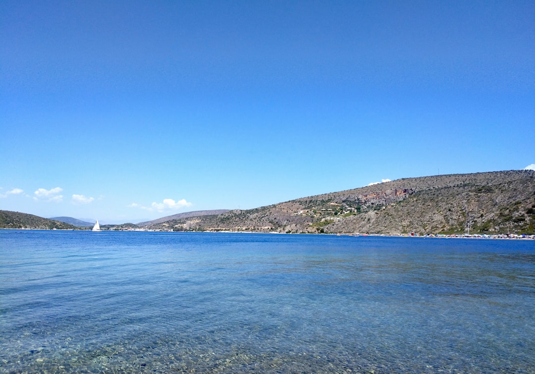 blue sea near green mountain under blue sky during daytime