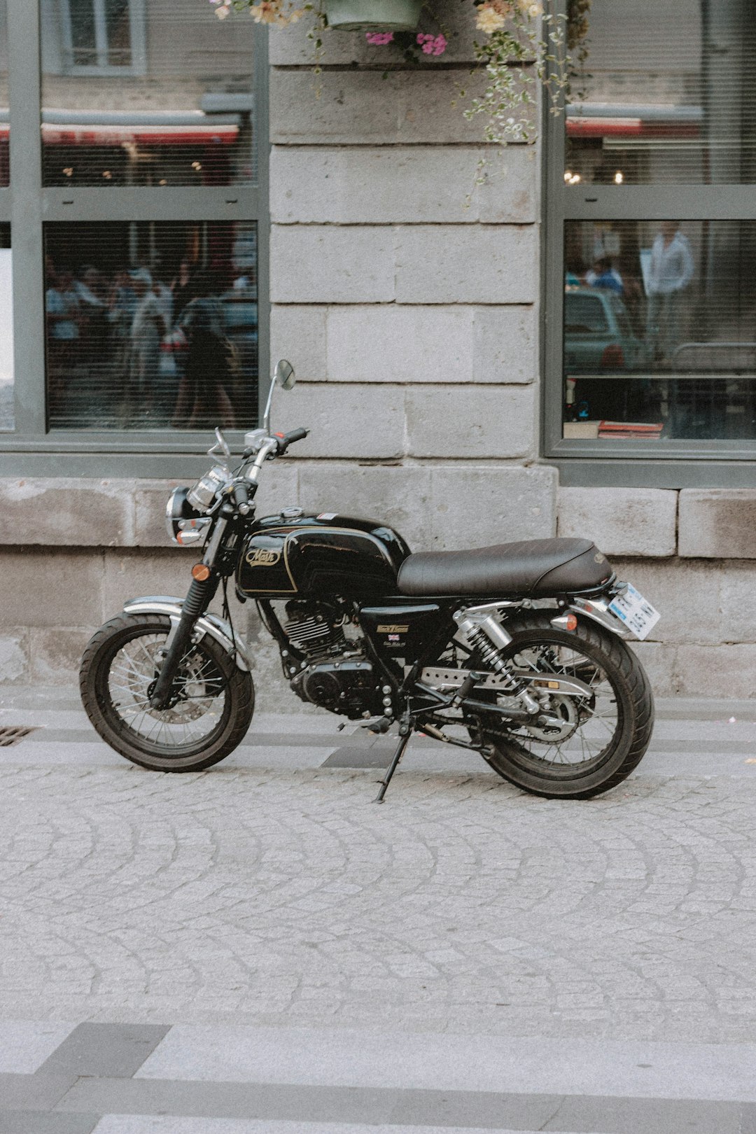 black and silver standard motorcycle parked beside brown brick wall
