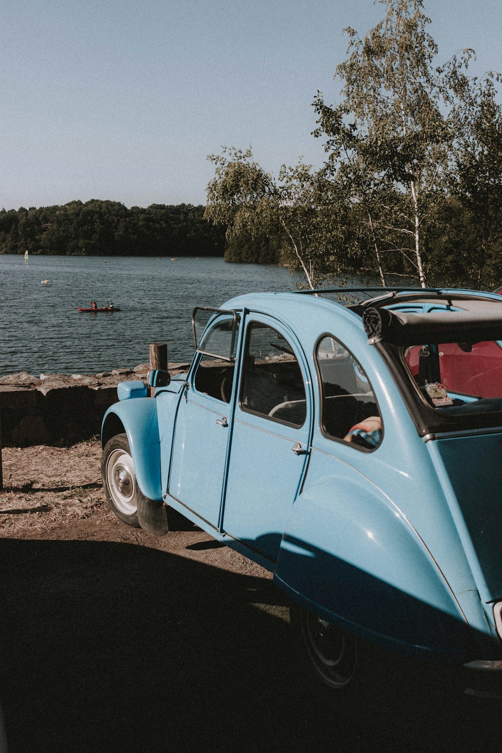 blue and white vintage car parked beside body of water during daytime