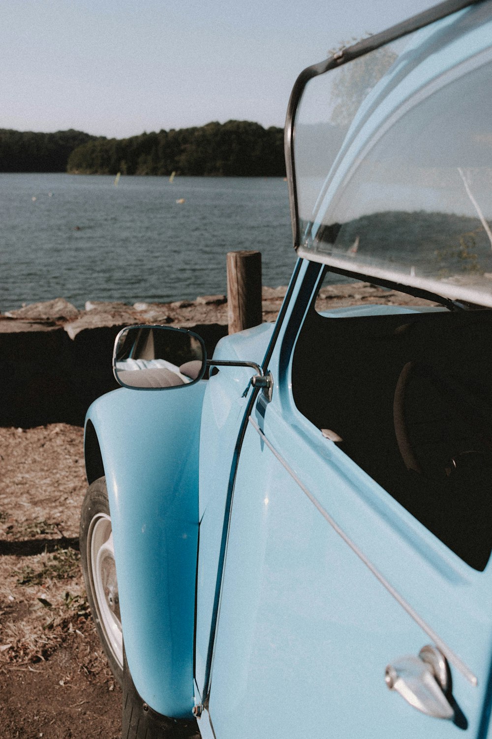 blue and white vintage car on brown sand during daytime