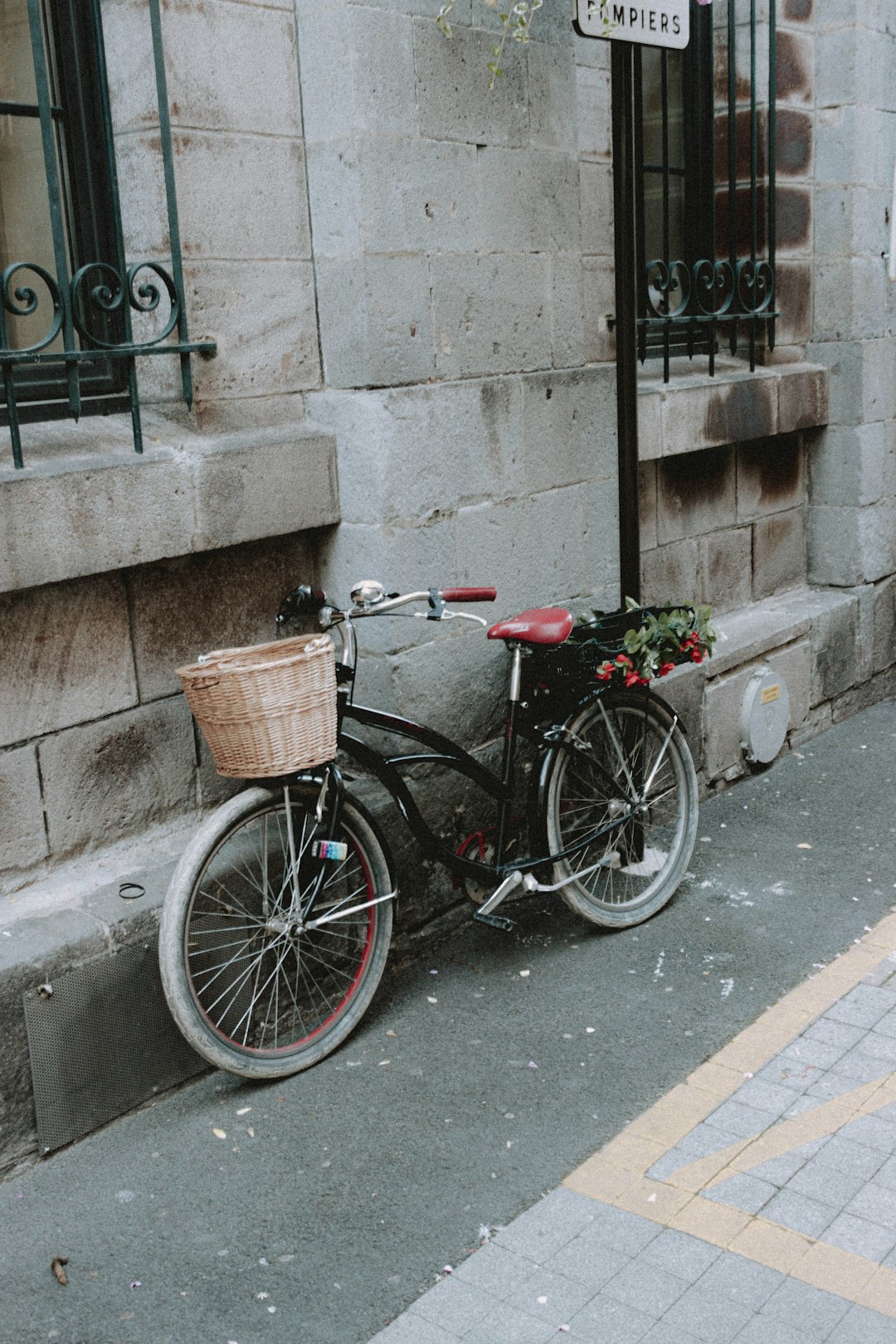 black city bike parked beside gray concrete wall