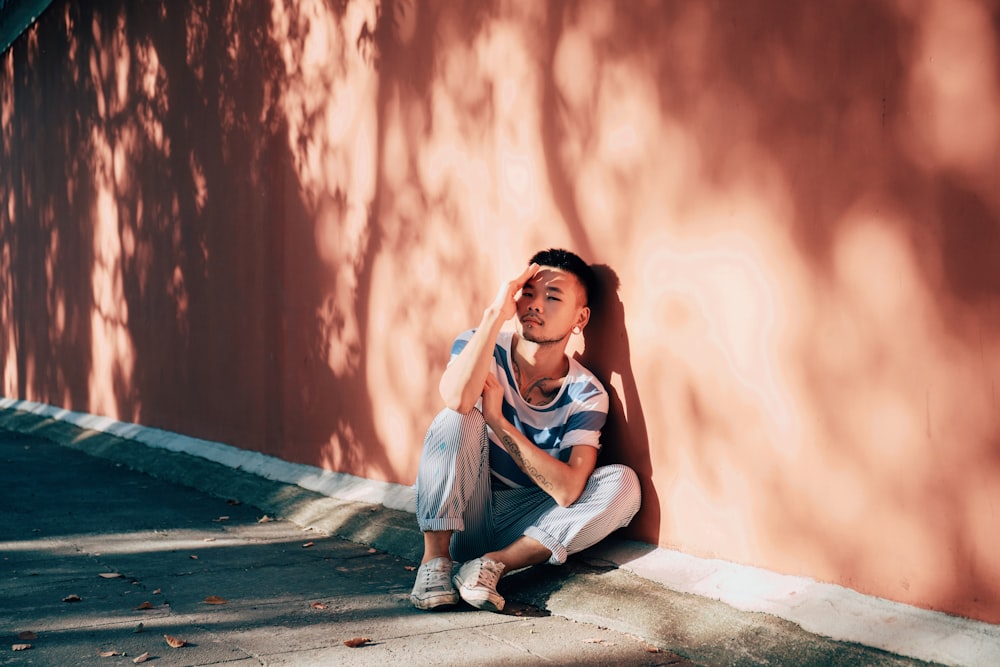 woman in blue sleeveless shirt and blue denim jeans sitting on concrete floor