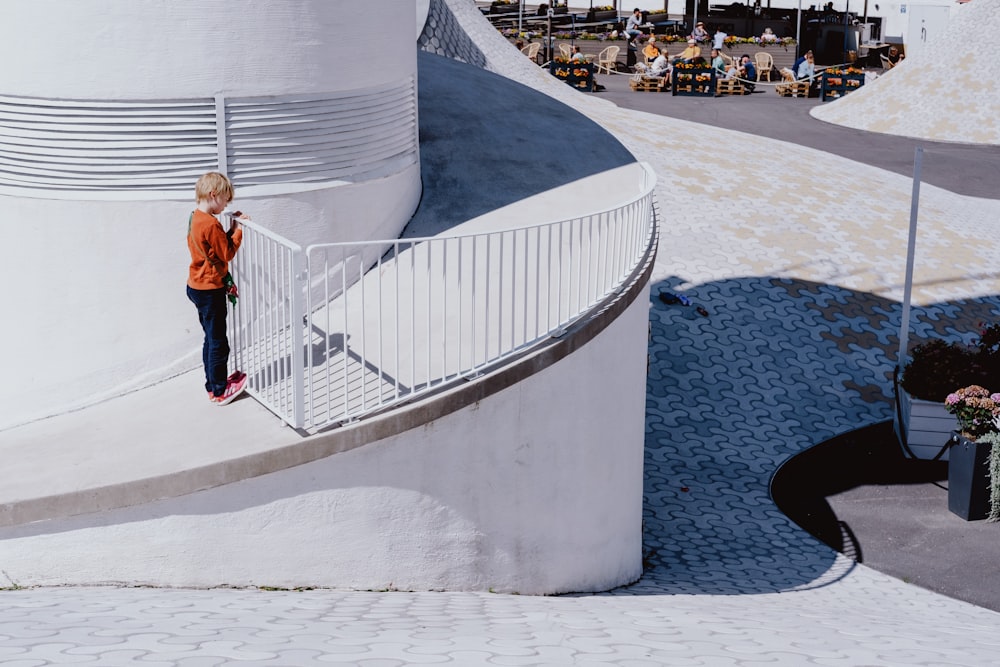 girl in white shirt and black pants walking on white concrete stairs during daytime