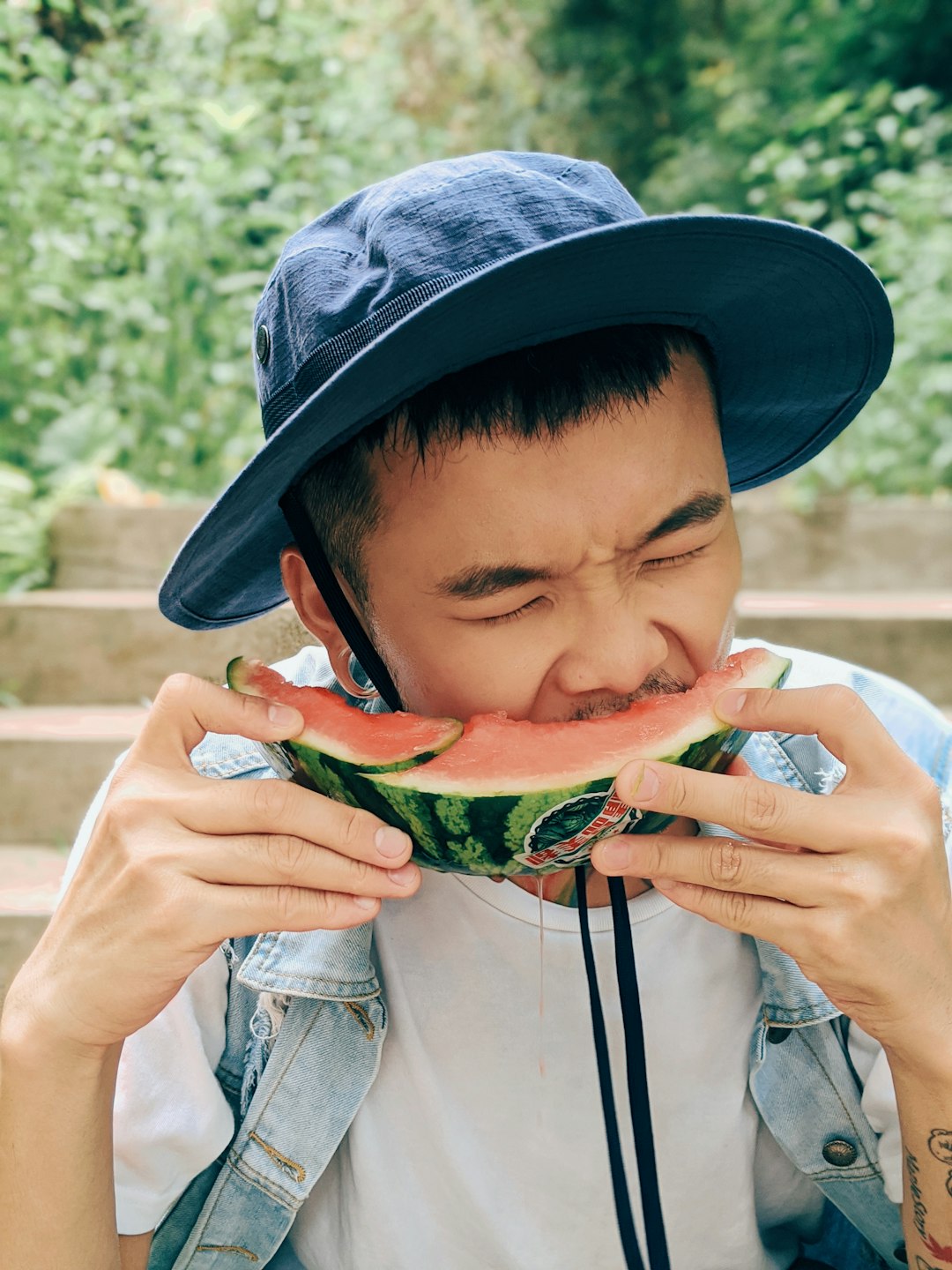 boy in grey hat holding green and yellow watermelon