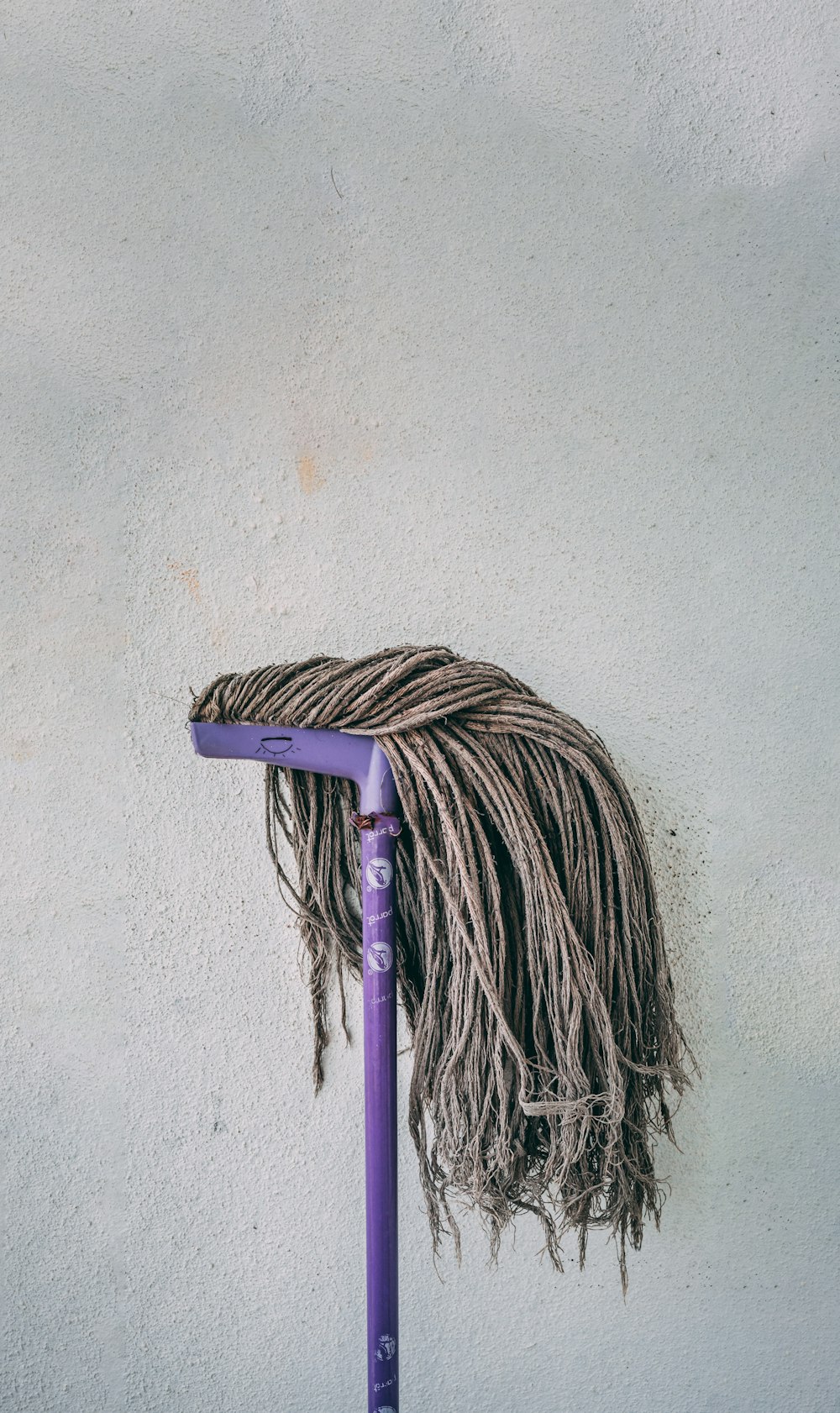 vadrouille violette et blanche appuyée sur un mur blanc