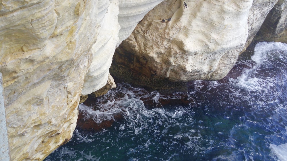 white and brown rock formation beside body of water during daytime