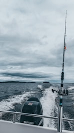 A sturdy center console boat cutting through waves with a fisherman casting lines from the deck.