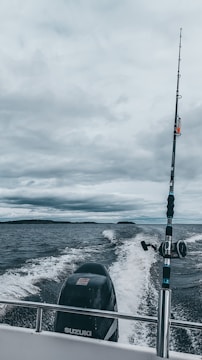 A sturdy center console boat cutting through waves with a fisherman casting lines from the deck.