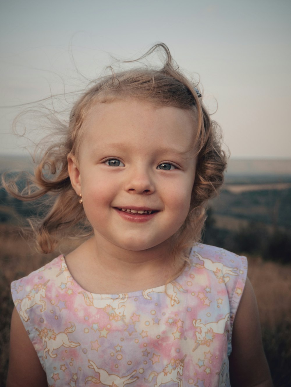 girl in white pink and green floral crew neck shirt smiling