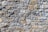 A close-up view of a textured stone wall, with irregularly shaped stones in varying shades of gray and brown, meticulously fitted together to form a solid structure.