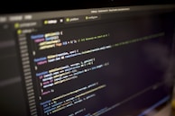 Close-up of hands typing JavaScript code on a modern keyboard.