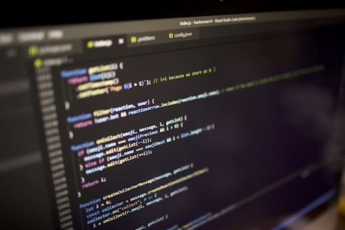 Close-up view of a computer screen displaying a code editor with JavaScript code. The code is color-coded, showing various functions, variables, and comments. The editor interface includes tabs and a menu bar, indicating an active coding session.