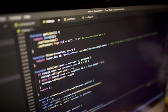 Close-up view of a computer screen displaying a code editor with JavaScript code. The code is color-coded, showing various functions, variables, and comments. The editor interface includes tabs and a menu bar, indicating an active coding session.