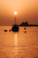 silhouette of boat on sea during sunset