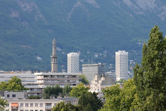 white concrete building near green trees during daytime in Grenoble France
