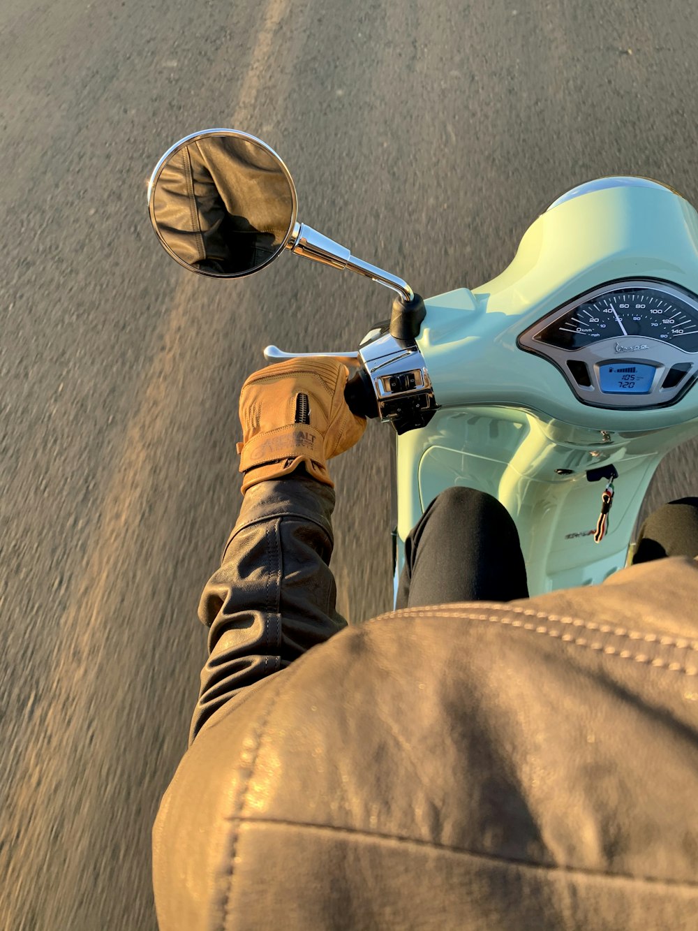 person in brown pants riding white and black motorcycle during daytime