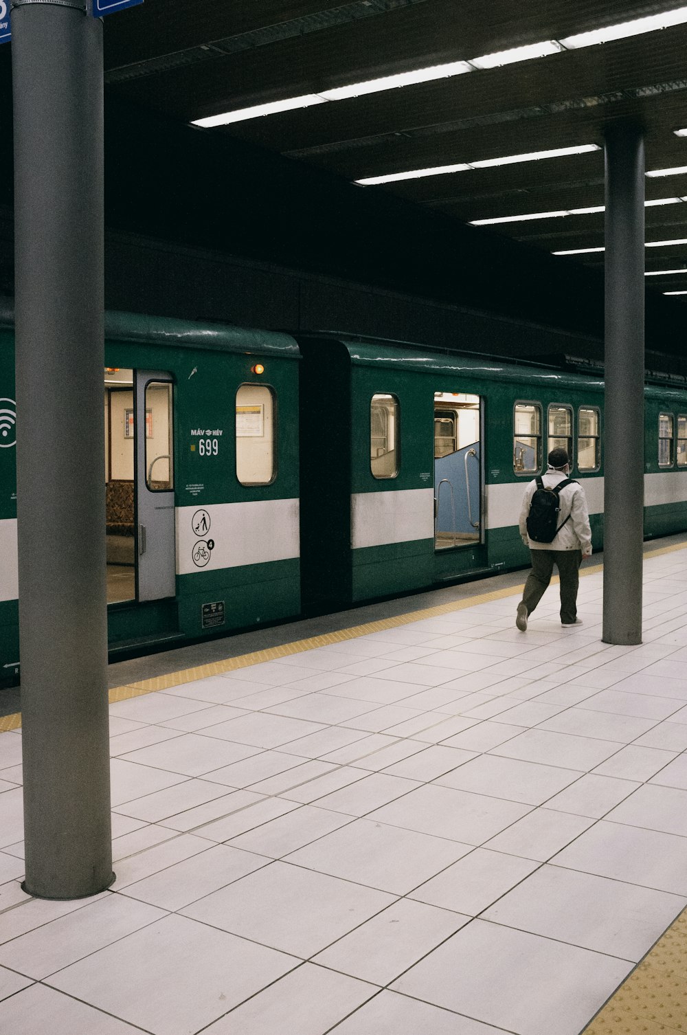man in black jacket standing beside green train
