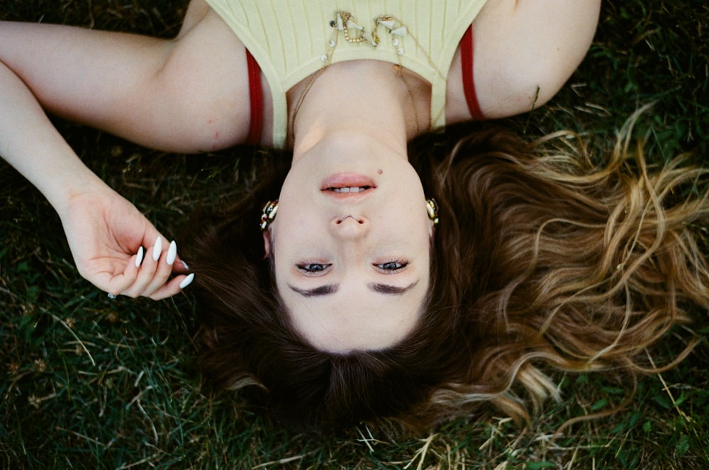 woman in red and white tank top lying on green grass
