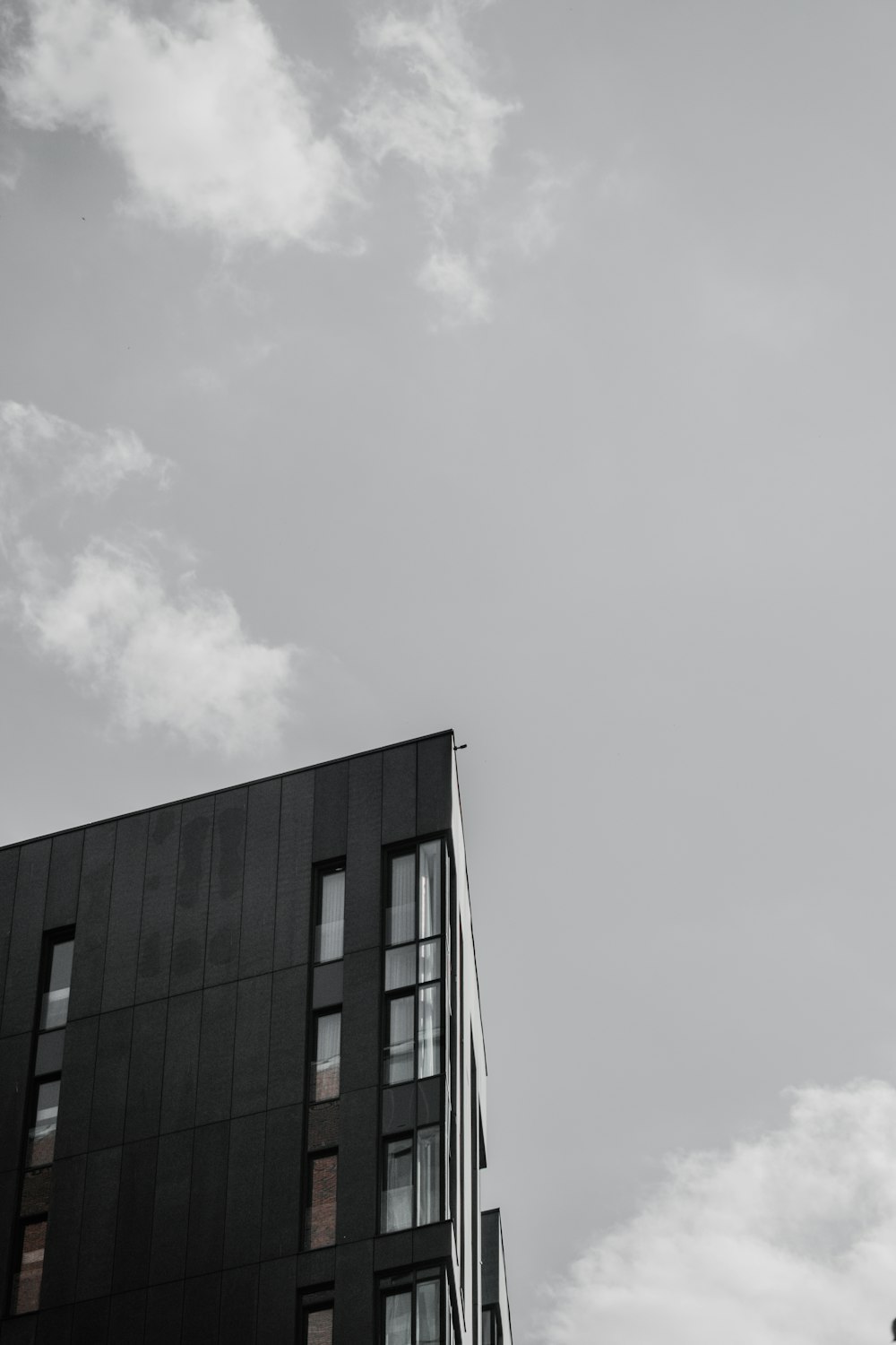 昼間の白い雲の下の黒いコンクリートの建物