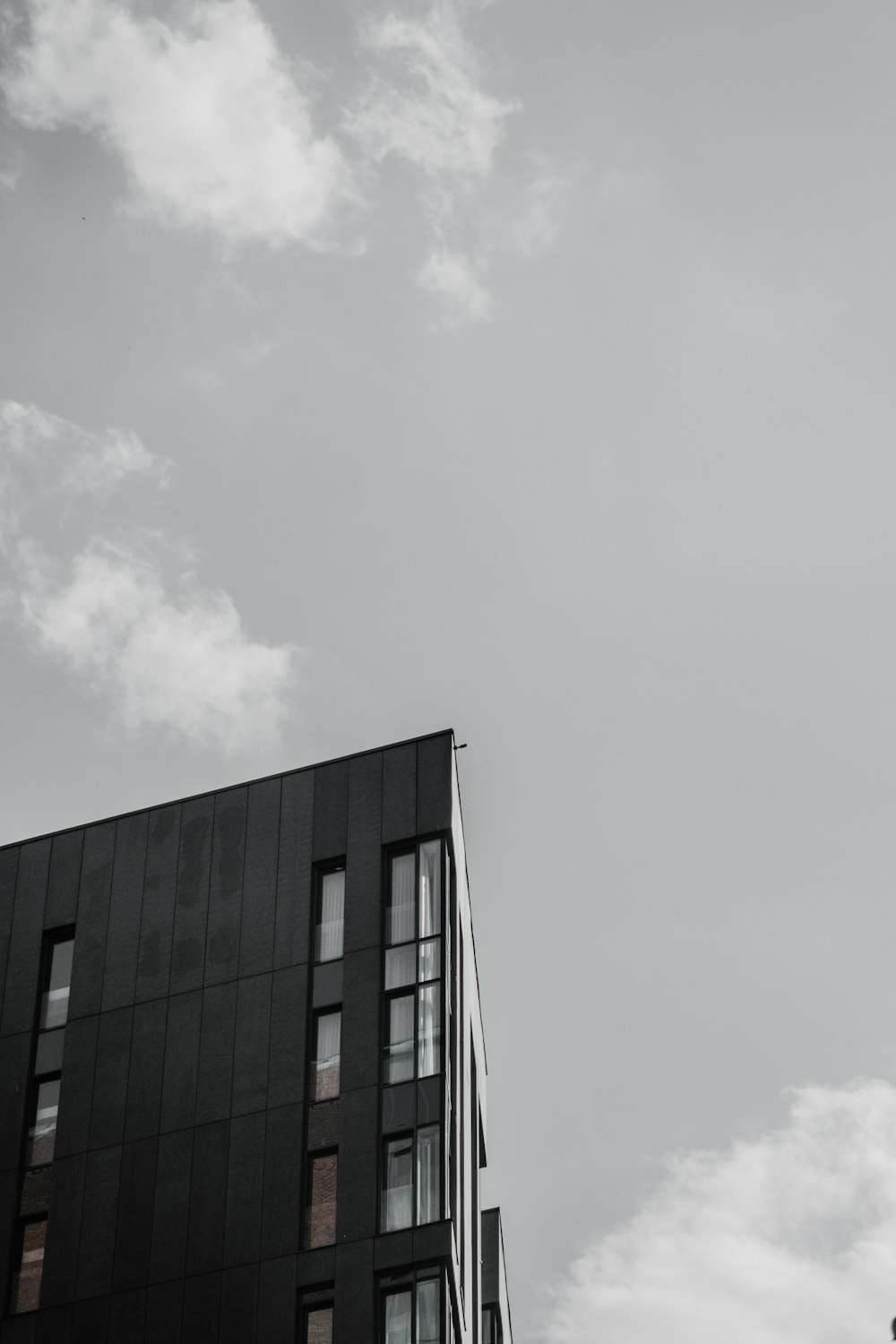 Edificio de hormigón negro bajo nubes blancas durante el día